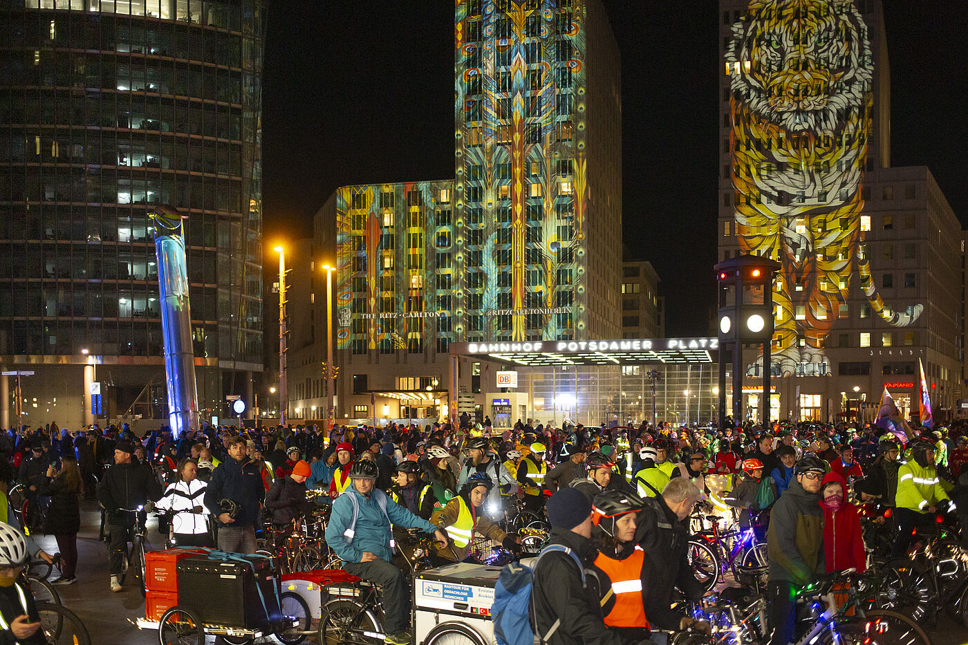 Lichterfahrt 2024 Potsdamer Platz Menschen mit Fahrrädern auf dem Potsdamer Platz, Türme angestrahlt mit bunten Motiven