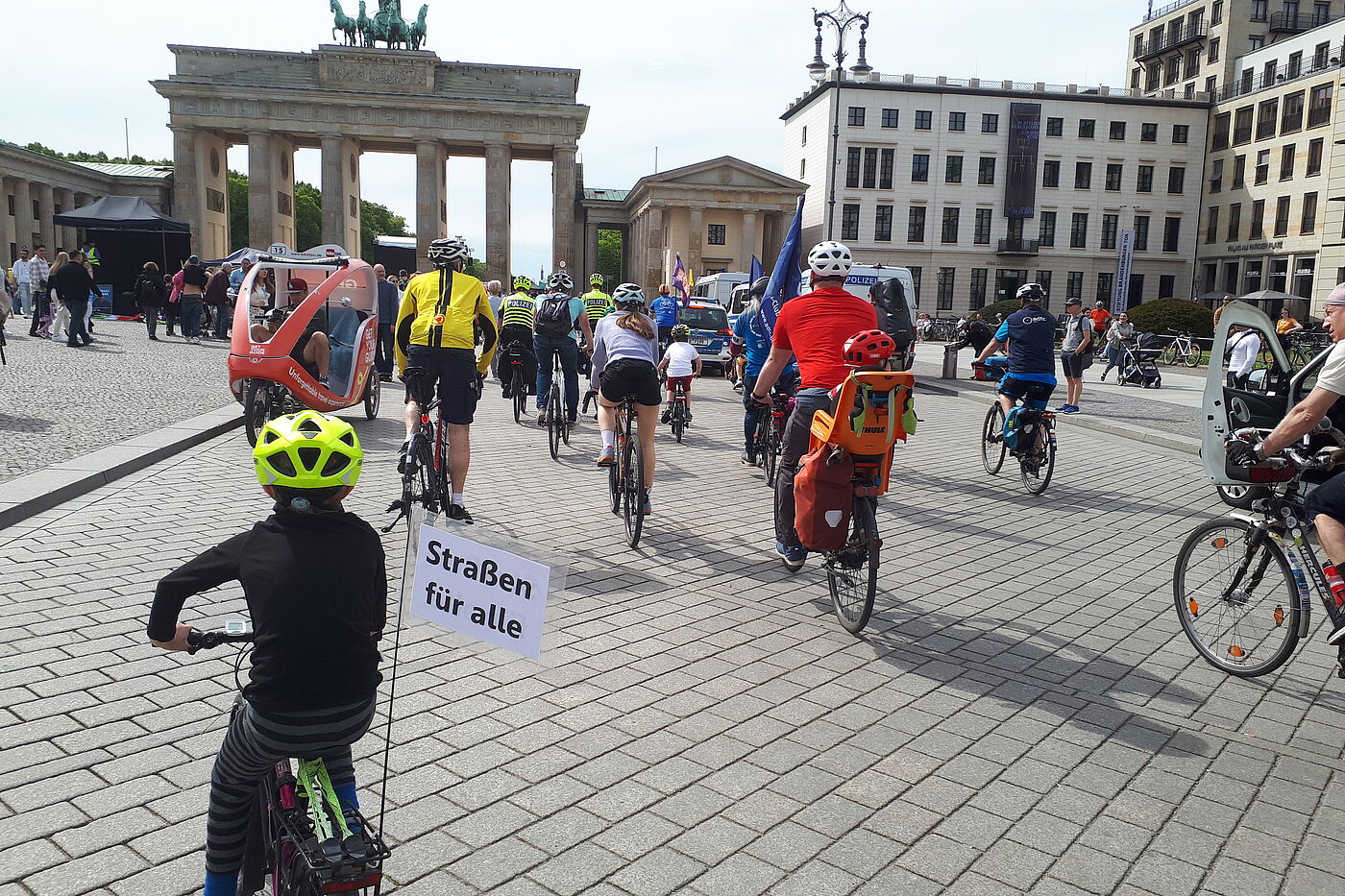 Kinder und Erwachsene fahren auf das Brandenburger Tor zu