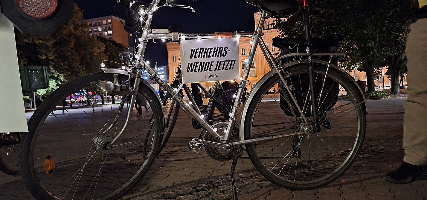 Lichterfahrt 2024 ein silbernes Fahrrad mit Lichterkette und Schild auf dem steht: Verkehrswende jetzt