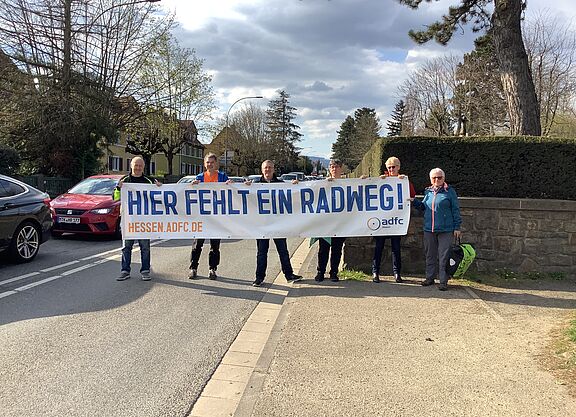 Frankfurter Landstraße: Radweg fehlt Personengruppe hält Banner hoch "Hier fehlt ein RAdweg"