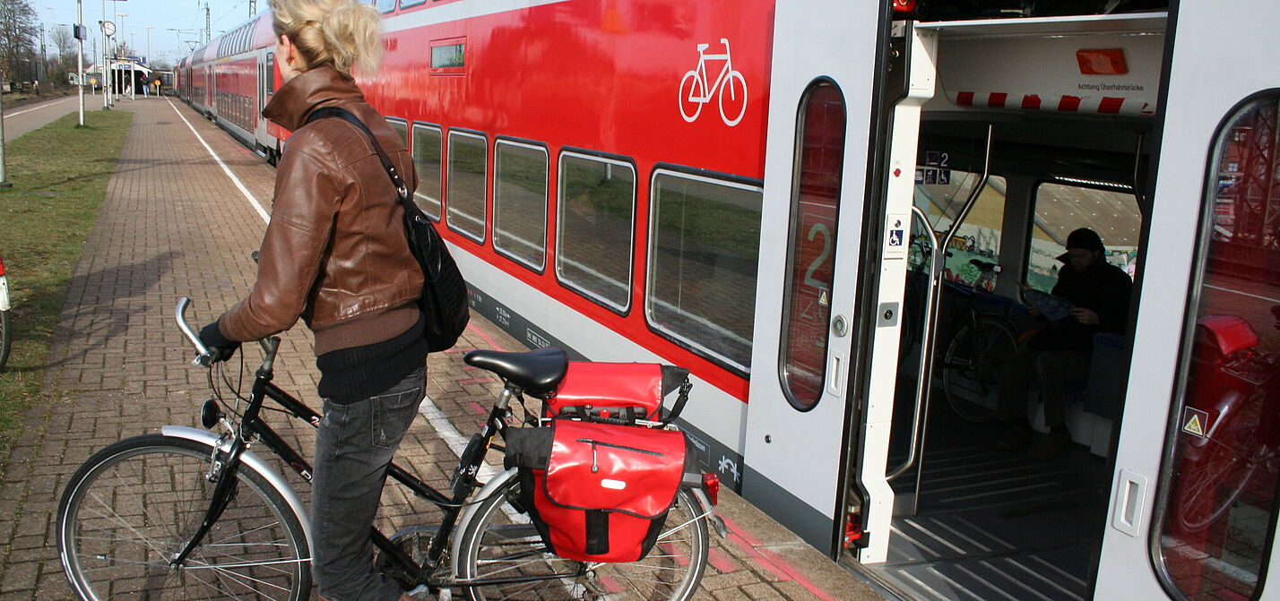 Frau mit Rad steigt aus Regionalzug